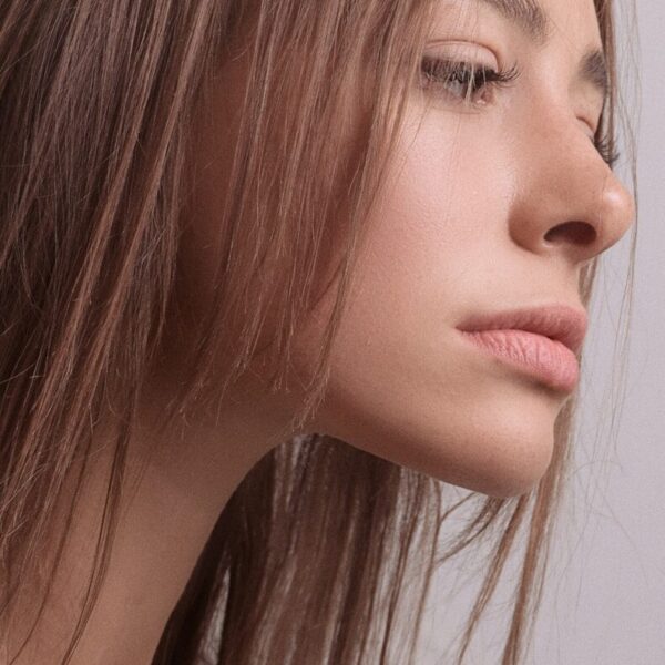 a close up of a woman's face with her hair blowing in the wind